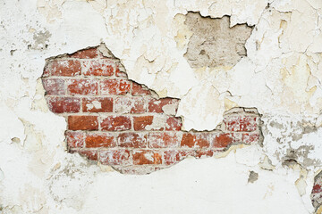 Texture of an old brick wall with damaged plaster and cracked paint.