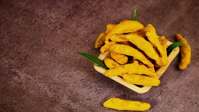 Dry Turmeric arranged in a white bowl with wooden texture or background,Turmeric rotation with selective focus