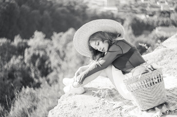 Black and white portrait of stylish girl in straw hat posing on a background of the city.