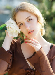 Close-up portrait of a cute blonde with a white flower in her hand. Vintage tone..Soft blur...