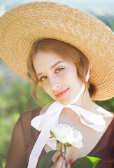 Close-up portrait of a sweet blonde in a straw hat at sunset. Vintage tone..Soft blur background