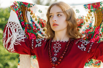 Portrait of a serious blonde in traditional national clothes posing with a scarf on her head.