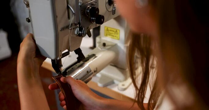 Young designer sewing leather in workshop