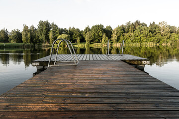 Wet wooden pier in smooth water of lake