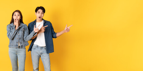 Two Young good looking asian couple using isolated on yellow background presenting to copy space