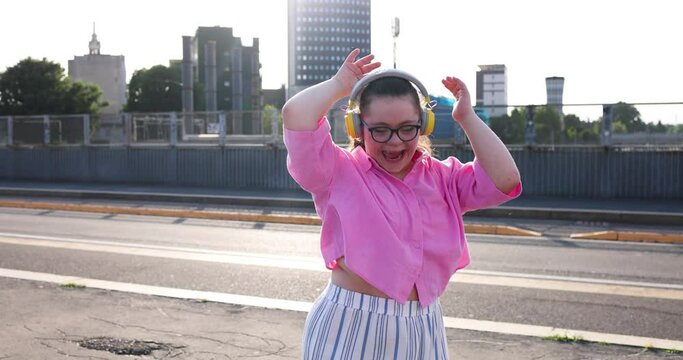 Girl with down syndrome dancing in the street wearing headphones