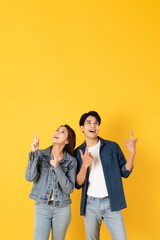 Two Young good looking asian couple using isolated on yellow background presenting to copy space feeling excited