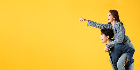 Two Young good looking asian couple using isolated on yellow background presenting to copy space feeling excited