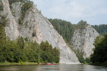 People raft on catamarans on a mountain river, a vacation on a water trip, rocks hang over the...