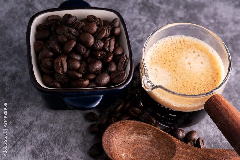 Wall mural Hot coffee with roasted coffee beans on a cement floor