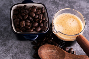 Hot coffee with roasted coffee beans on a cement floor