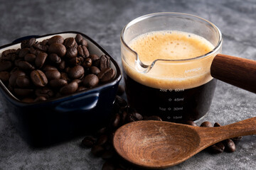 Hot coffee with roasted coffee beans on a cement floor