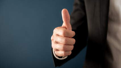 Businessman showing a thumbs up gesture over blue background with copy space