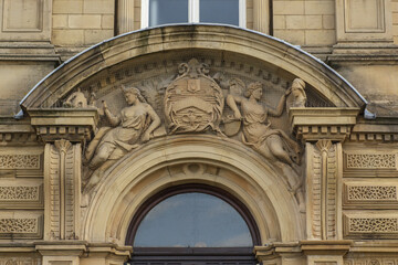 Thomas Milnes' statues depicting Science and the Arts either side of Titus Salt's coat of arms in the arch above the door of Victoria Hall in the Unesco World Heritage Site of Saltaire in Yorkshire