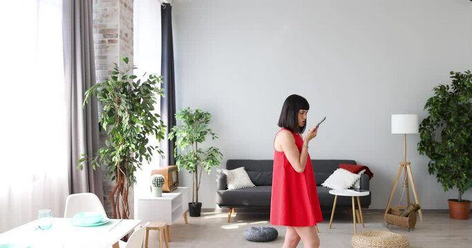 Woman Speaking Voice Mail On Smartphone Walking In Living Room