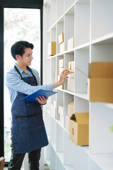 A portrait of a small startup, an SME owner, an Asian male entrepreneur checking orders to arrange...