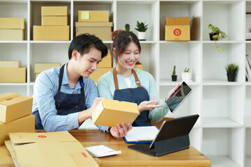 Obraz premium Portrait of a small start-up and SME owner, an Asian male and female entrepreneur checking orders and packing for customers, self-employed, freelance, online selling