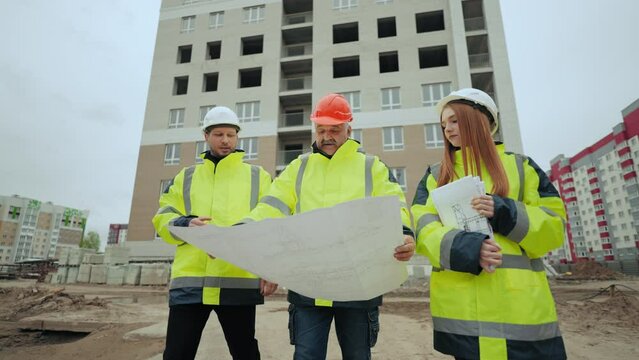 engineering team are inspecting building site, foreman is viewing constructing plan on paper