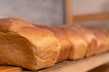 Close-up of freshly baked bread on wooden shelves. Production of bakery products