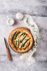 Quiche. Homemade asparagus pie or quiche with cheese, pecorino, bacon and spinach on gray concrete light table background. Asparagus and cheese tart. French Quiche. Top view.