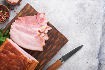 Whole Smoked Slab Bacon. Brisket. Sliced smoked gammon on a wooden table with rosemary, parsley,...