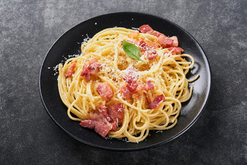 Carbonara pasta. Spaghetti with pancetta, egg, parmesan cheese and cream sauce on old dark black concrete table background. Traditional italian cuisine and dish. Pasta alla carbonara. Top view.