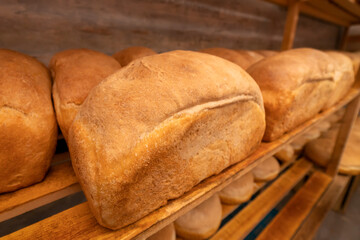 Close-up of freshly baked bread on wooden shelves. Production of bakery products
