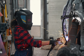 Female mechanic protecting eyes while welding metal