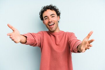 Young caucasian man isolated on blue background feels confident giving a hug to the camera.