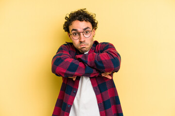 Young caucasian man isolated on yellow background shrugs shoulders and open eyes confused.