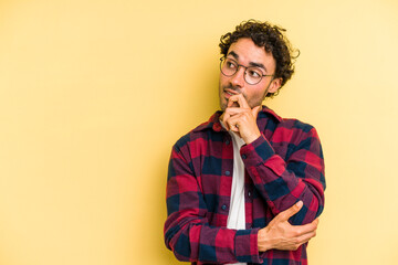 Young caucasian man isolated on yellow background relaxed thinking about something looking at a copy space.