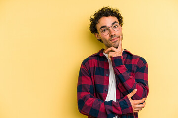 Young caucasian man isolated on yellow background looking sideways with doubtful and skeptical expression.
