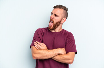 Fototapeta premium Young caucasian man isolated on blue background funny and friendly sticking out tongue.