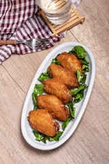 Herb fried chicken wings in white plate on wooden floor