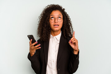 Young business Brazilian woman holding mobile phone isolated on white background pointing upside...