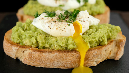 poached egg with runny egg yolk over bread toast with mashed avocado spread
