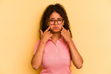 Young Brazilian woman isolated on yellow background crying, unhappy with something, agony and...