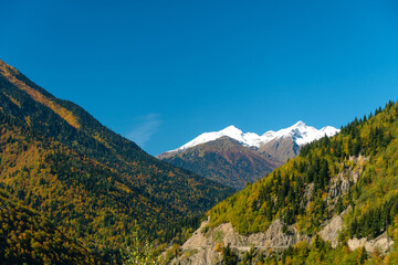 Beautiful, atmospheric view of the mountains, snowy peaks, serpentine, on a sunny bright autumn day, Svaneti, Georgia. Magnificent autumn mountain landscape on a sunny day