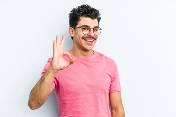 Young caucasian man isolated on blue background cheerful and confident showing ok gesture.