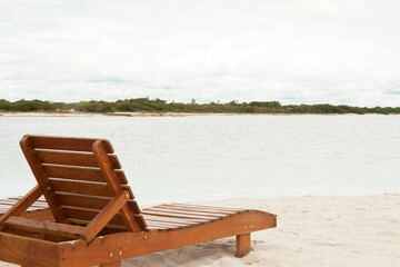Fototapeta premium Deckchair lounger on the edge of the beach in summer with nice tropical weather. Resort by the sea in Brazil. Beach chair concept. Tourism concept. Copy space.