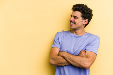 Young caucasian man isolated on yellow background smiling confident with crossed arms.