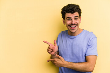 Young caucasian man isolated on yellow background excited pointing with forefingers away.