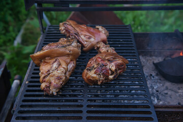 Several traditional Bavarian German roasted pork knuckles slowly cooked at rotating broiling rack grill spit, close up, low angle side view. barbecue. the concept of cooking on an open fire.