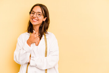 Young nutritionist hispanic woman isolated on yellow background smiling and raising thumb up