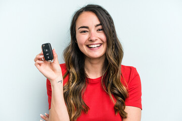 Fototapeta premium Young caucasian woman holding car keys isolated on blue background laughing and having fun.
