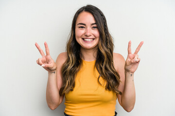 Young caucasian woman isolated on white background showing victory sign and smiling broadly.