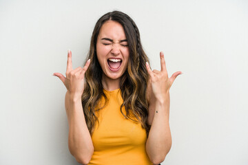 Young caucasian woman isolated on white background showing a horns gesture as a revolution concept.