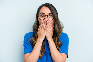Young caucasian woman isolated on blue background shocked, covering mouth with hands, anxious to discover something new.