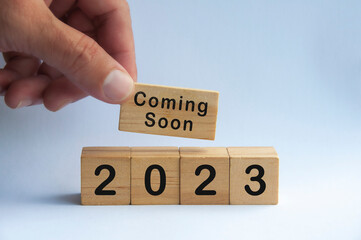 Hand holding wooden block with text - 2023 coming soon. New year concept and copy space