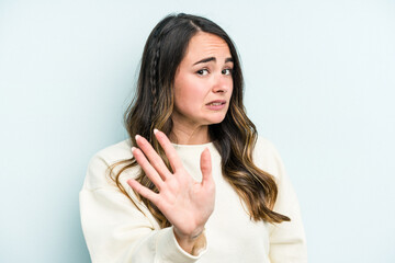 Young caucasian woman isolated on blue background rejecting someone showing a gesture of disgust.
